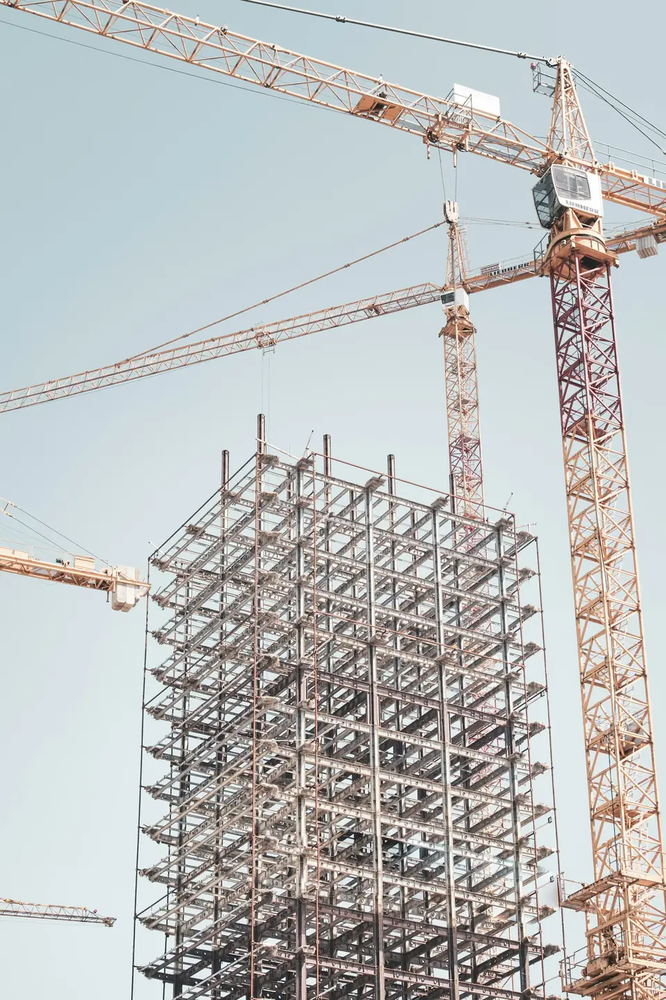 Estrutura metálica de um edifício em construção entre gruas
